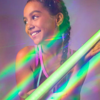 Girl smiling with a neon glowing stick, showcasing vibrant dance energy from Sylvia P's Dance Party Collection.