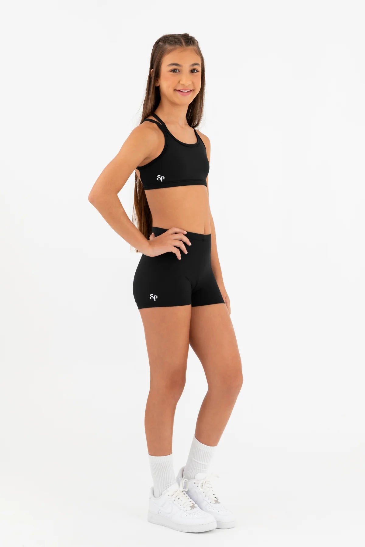Person wearing a black sports bra and shorts set on a white background